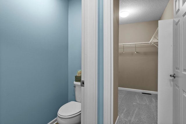 14111 Abercorn Ave, Rosemount, MN 55068 - bathroom with a textured ceiling, toilet, baseboards, and a walk in closet