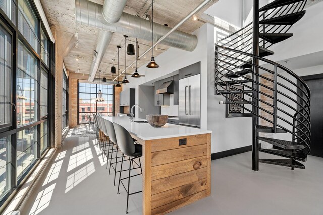 525 3rd St N Unit 511, Minneapolis, MN 55401 - kitchen with wall chimney exhaust hood, a kitchen island with sink, concrete floors, hanging light fixtures, and light countertops