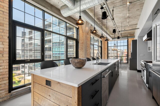 525 3rd St N Unit 511, Minneapolis, MN 55401 - kitchen with brick wall, appliances with stainless steel finishes, concrete floors, an island with sink, and decorative light fixtures