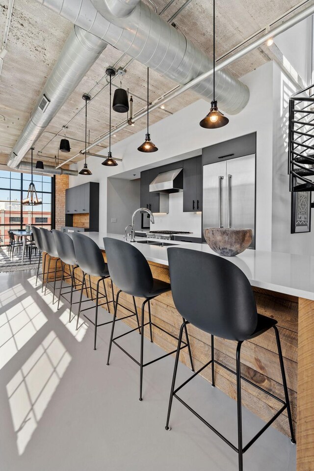 525 3rd St N Unit 511, Minneapolis, MN 55401 - kitchen featuring wall chimney exhaust hood, built in refrigerator, a kitchen breakfast bar, hanging light fixtures, and light countertops