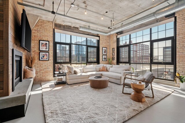 525 3rd St N Unit 511, Minneapolis, MN 55401 - living room featuring concrete flooring, brick wall, a towering ceiling, healthy amount of natural light, and a glass covered fireplace