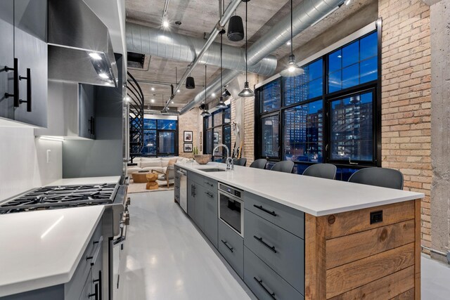 525 3rd St N Unit 511, Minneapolis, MN 55401 - kitchen featuring brick wall, gray cabinetry, open floor plan, light countertops, and an island with sink
