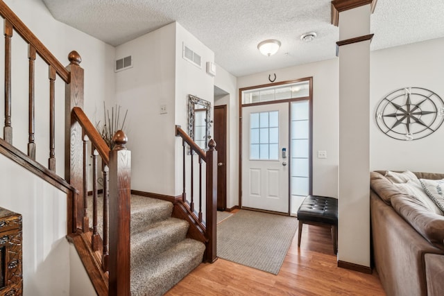 6665 Flycatcher Ln, Apple Valley, MN 55124 - entryway featuring stairway, light wood-type flooring, baseboards, a textured ceiling, and decorative columns