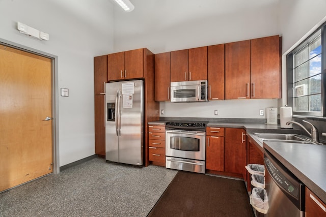 6665 Flycatcher Ln, Apple Valley, MN 55124 - kitchen featuring appliances with stainless steel finishes, a sink, brown cabinetry, dark countertops, and a towering ceiling