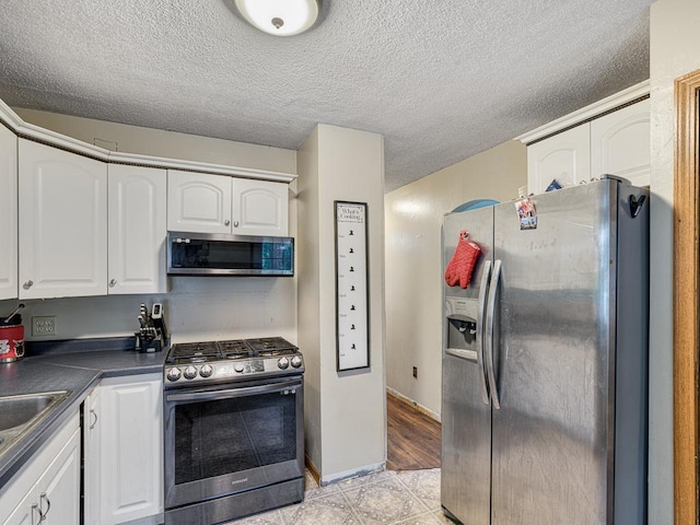 7338 Silver Lake Rd, Mounds View, MN 55112 - kitchen with stainless steel appliances, dark countertops, white cabinetry, and a textured ceiling