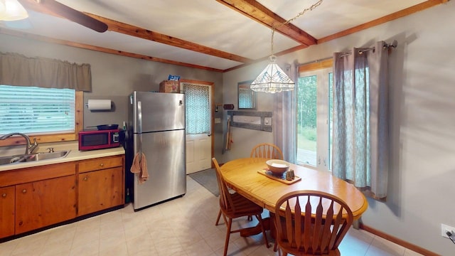 48408 Pillar Rd, Deer River, MN 56631 - kitchen featuring freestanding refrigerator, beamed ceiling, brown cabinetry, light countertops, and hanging light fixtures