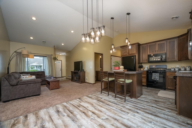 411 Ladd Ln, Osceola, WI 54020 - kitchen with black appliances, open floor plan, a kitchen island, light wood-style flooring, and a breakfast bar area