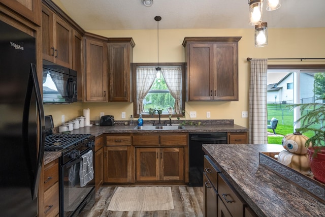 411 Ladd Ln, Osceola, WI 54020 - kitchen featuring black appliances, wood finished floors, pendant lighting, and dark stone countertops