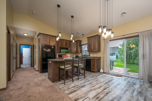 411 Ladd Ln, Osceola, WI 54020 - kitchen featuring black appliances, vaulted ceiling, a center island, a kitchen breakfast bar, and decorative light fixtures