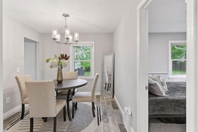 2505 Florida Ave N, Golden Valley, MN 55427 - dining room featuring a chandelier, wood finished floors, healthy amount of natural light, a textured ceiling, and baseboards