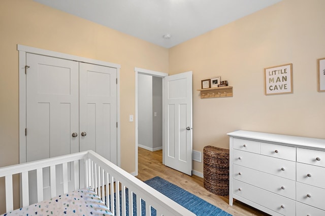 975 100th St NE, Monticello Twp, MN 55362 - bedroom with light wood finished floors, baseboards, a crib, and a closet