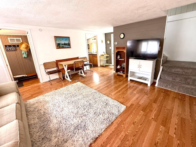 4231 Teal Ln NE, Bemidji, MN 56601 - living room featuring wood finished floors, a textured ceiling, stairs, and wooden walls