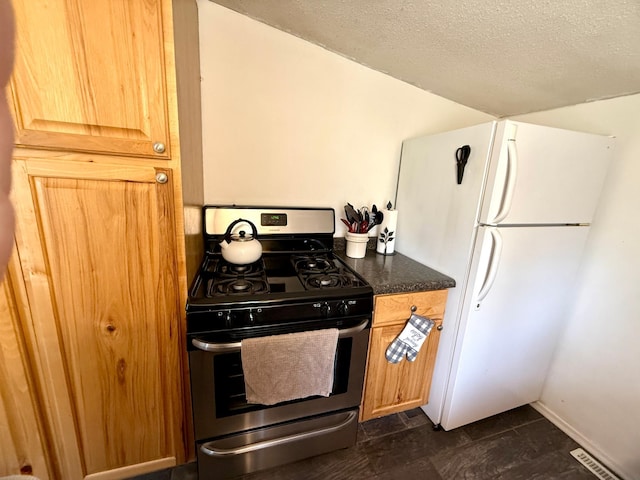 4231 Teal Ln NE, Bemidji, MN 56601 - kitchen featuring stainless steel gas range oven, freestanding refrigerator, a textured ceiling, dark stone countertops, and baseboards