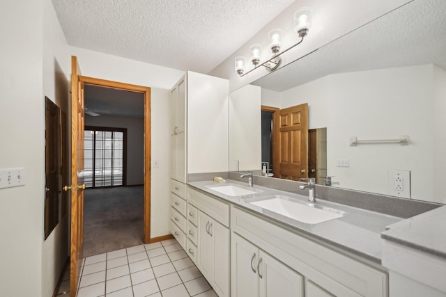 4311 Pond View Dr, White Bear Twp, MN 55110 - bathroom featuring tile patterned flooring, a textured ceiling, double vanity, and baseboards