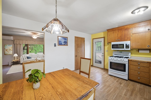 28748 Palm St NW, Isanti, MN 55040 - kitchen featuring white appliances, a wall mounted air conditioner, plenty of natural light, and light wood-style floors