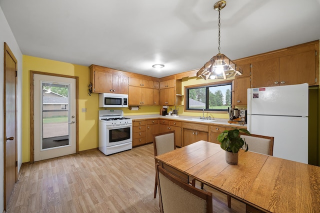 28748 Palm St NW, Isanti, MN 55040 - kitchen featuring white appliances, a sink, light countertops, light wood-style flooring, and pendant lighting
