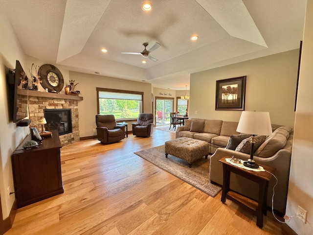 910 Lake Forest Cir, Detroit Lakes, MN 56501 - living room with a raised ceiling, a ceiling fan, light wood finished floors, a stone fireplace, and recessed lighting