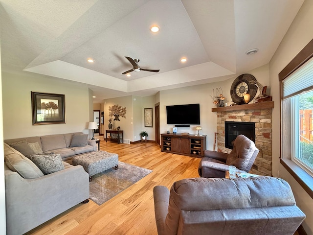 910 Lake Forest Cir, Detroit Lakes, MN 56501 - living area featuring a raised ceiling, baseboards, light wood finished floors, a fireplace, and a ceiling fan