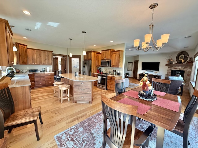 910 Lake Forest Cir, Detroit Lakes, MN 56501 - dining space with a chandelier, light wood finished floors, a stone fireplace, and recessed lighting