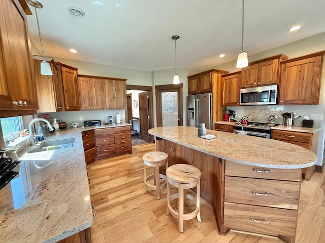 910 Lake Forest Cir, Detroit Lakes, MN 56501 - kitchen with appliances with stainless steel finishes, a sink, brown cabinetry, a kitchen breakfast bar, and a center island