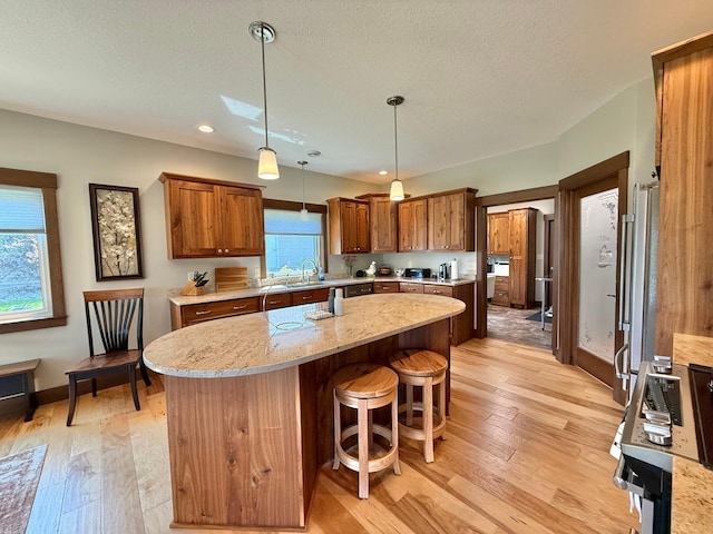 910 Lake Forest Cir, Detroit Lakes, MN 56501 - kitchen with a center island, a sink, light wood-type flooring, pendant lighting, and brown cabinetry