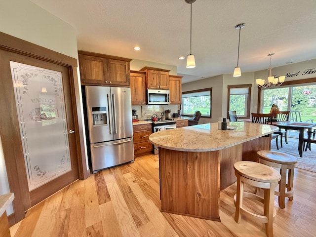 910 Lake Forest Cir, Detroit Lakes, MN 56501 - kitchen with appliances with stainless steel finishes, brown cabinets, light wood-style floors, a center island, and a chandelier