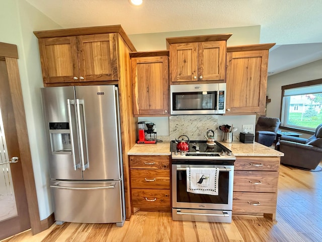 910 Lake Forest Cir, Detroit Lakes, MN 56501 - kitchen with appliances with stainless steel finishes, light wood-style floors, brown cabinetry, and decorative backsplash