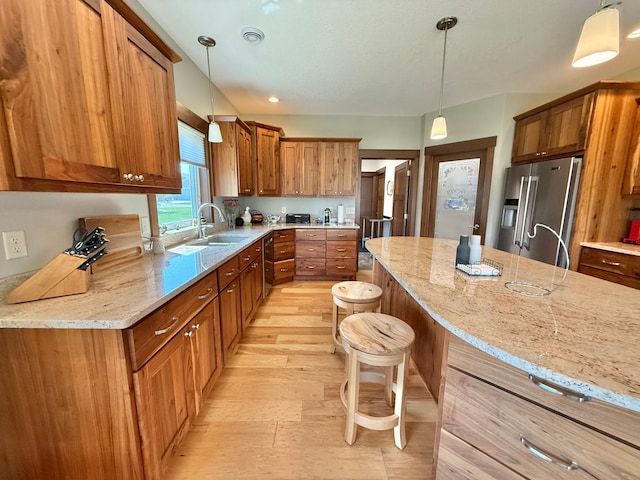910 Lake Forest Cir, Detroit Lakes, MN 56501 - kitchen featuring high end fridge, a sink, a kitchen bar, brown cabinetry, and light stone counters