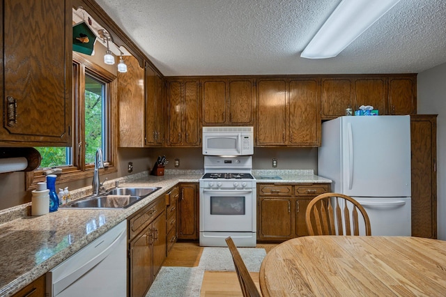4781 Zealand Ave N, New Hope, MN 55428 - kitchen with white appliances, a textured ceiling, brown cabinetry, light countertops, and light wood finished floors