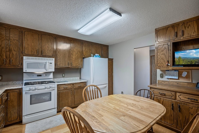 4781 Zealand Ave N, New Hope, MN 55428 - kitchen with white appliances, a textured ceiling, light wood-style flooring, light countertops, and brown cabinets