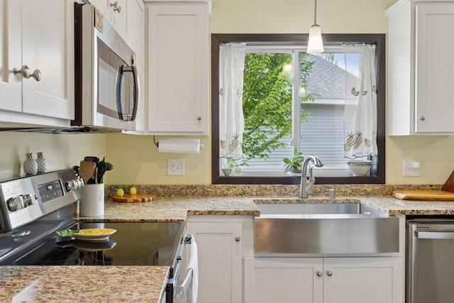 134 9th Ave NE, Isanti, MN 55040 - kitchen featuring appliances with stainless steel finishes, a sink, white cabinets, decorative light fixtures, and light stone counters