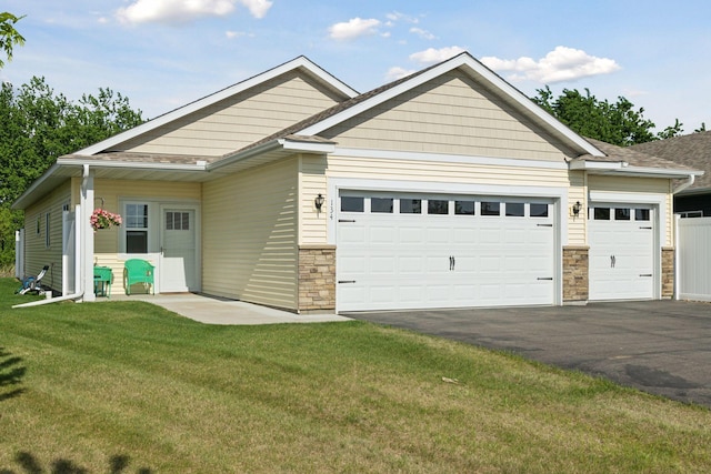 134 9th Ave NE, Isanti, MN 55040 - view of front of property featuring a garage, driveway, stone siding, and a front lawn