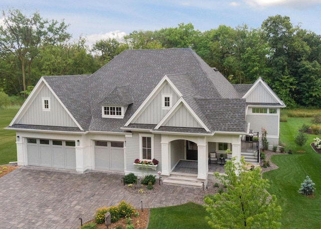 677 Shawnee Woods Rd, Medina, MN 55340 - view of front of house with board and batten siding, decorative driveway, a front lawn, covered porch, and roof with shingles
