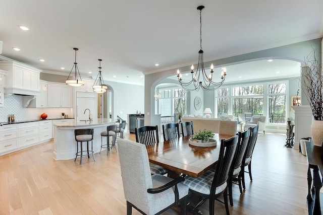 677 Shawnee Woods Rd, Medina, MN 55340 - dining space with arched walkways, a chandelier, light wood-style flooring, ornamental molding, and recessed lighting