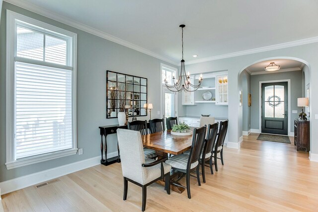677 Shawnee Woods Rd, Medina, MN 55340 - dining space featuring arched walkways, light wood-style floors, baseboards, healthy amount of natural light, and ornamental molding