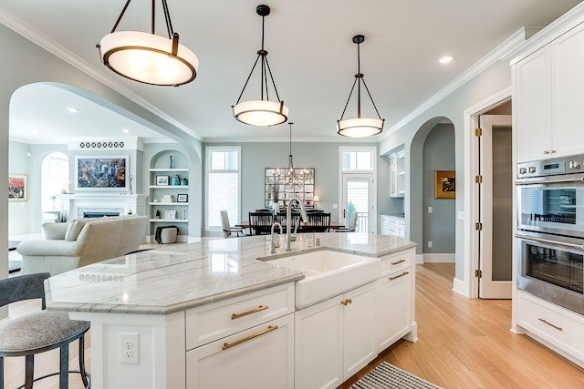 677 Shawnee Woods Rd, Medina, MN 55340 - kitchen with a sink, arched walkways, stainless steel double oven, light wood-style flooring, and white cabinetry