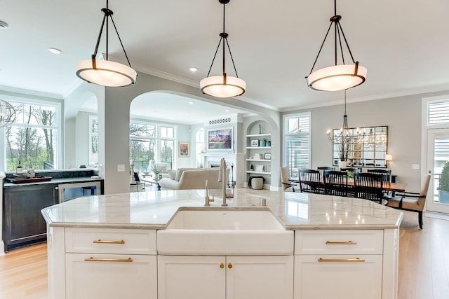 677 Shawnee Woods Rd, Medina, MN 55340 - kitchen with a sink, open floor plan, ornamental molding, light wood-style floors, and a chandelier