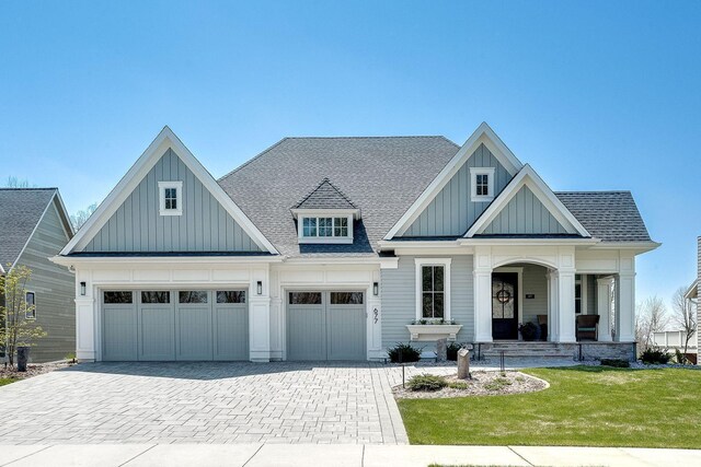 677 Shawnee Woods Rd, Medina, MN 55340 - modern farmhouse featuring board and batten siding, decorative driveway, a front yard, a shingled roof, and covered porch
