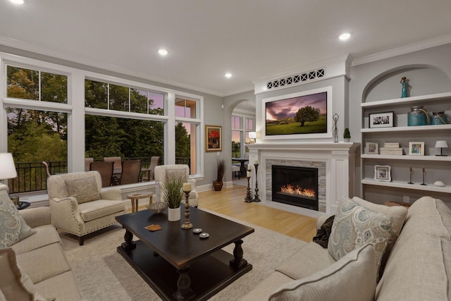 677 Shawnee Woods Rd, Medina, MN 55340 - living area with ornamental molding, arched walkways, light wood-type flooring, recessed lighting, and a fireplace with flush hearth