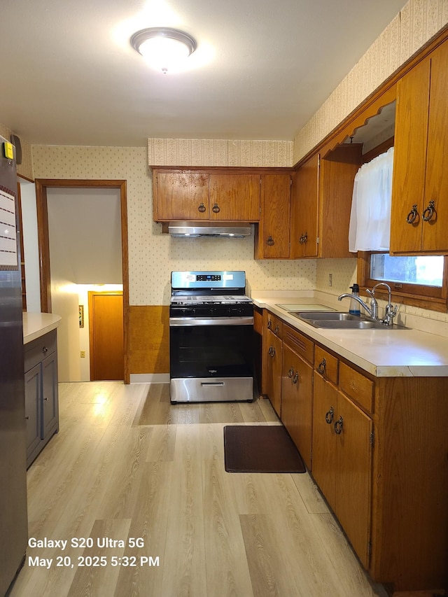 7036 Regent Ave N, Brooklyn Center, MN 55429 - kitchen featuring gas stove, wallpapered walls, under cabinet range hood, a sink, and brown cabinetry