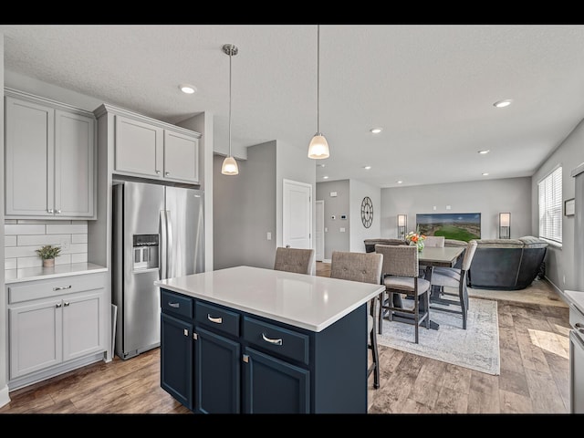 1750 Astoria Dr, Shakopee, MN 55379 - kitchen featuring stainless steel fridge with ice dispenser, blue cabinetry, light wood finished floors, light countertops, and recessed lighting