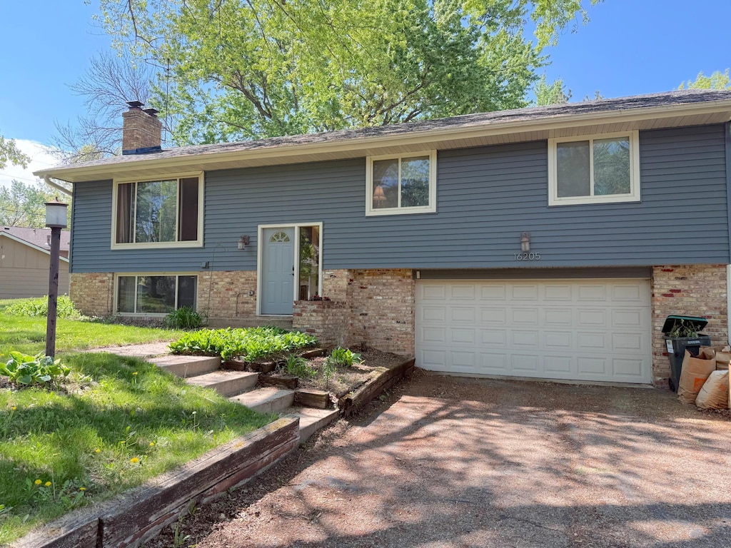 16205 5th Ave N, Plymouth, MN 55447 - raised ranch featuring brick siding, a garage, a chimney, and driveway