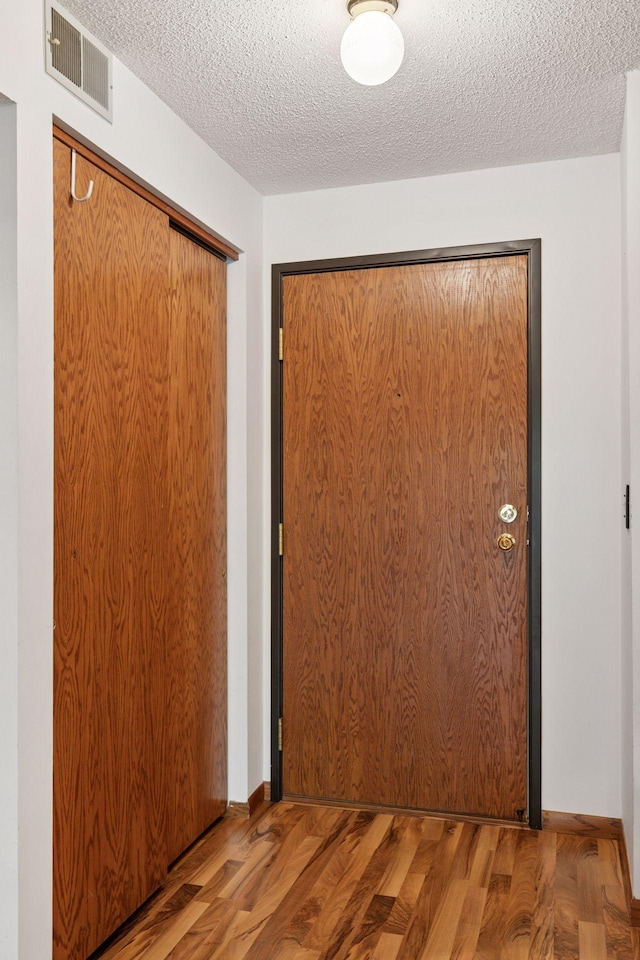1225 Ferndale St N Unit B16, Maplewood, MN 55119 - hall featuring wood finished floors, a textured ceiling, and baseboards