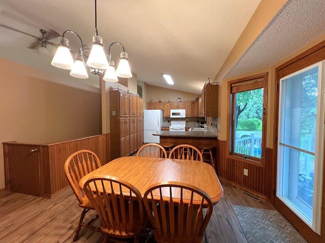1715 Hansen Dr SW, Willmar, MN 56201 - dining room with light wood finished floors, vaulted ceiling, a chandelier, wooden walls, and a textured ceiling