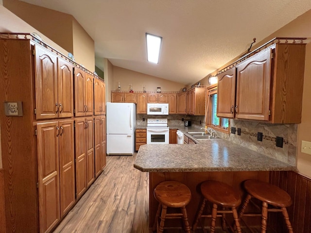 1715 Hansen Dr SW, Willmar, MN 56201 - kitchen with white appliances, a peninsula, vaulted ceiling, light wood-type flooring, and a breakfast bar area