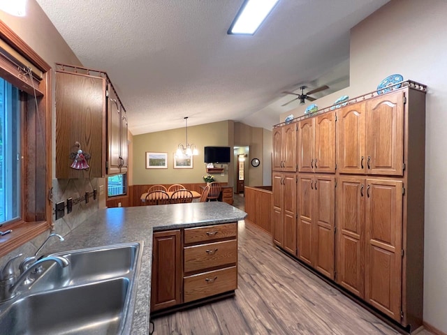 1715 Hansen Dr SW, Willmar, MN 56201 - kitchen featuring a sink, a peninsula, wood finished floors, lofted ceiling, and decorative light fixtures