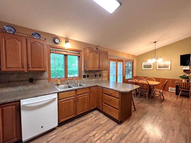 1715 Hansen Dr SW, Willmar, MN 56201 - kitchen featuring white dishwasher, a peninsula, light wood-style flooring, a sink, and lofted ceiling