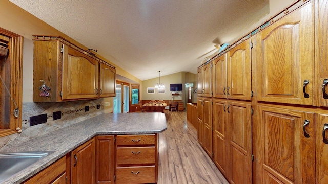 1715 Hansen Dr SW, Willmar, MN 56201 - kitchen featuring light wood-style floors, lofted ceiling, a peninsula, a textured ceiling, and brown cabinets