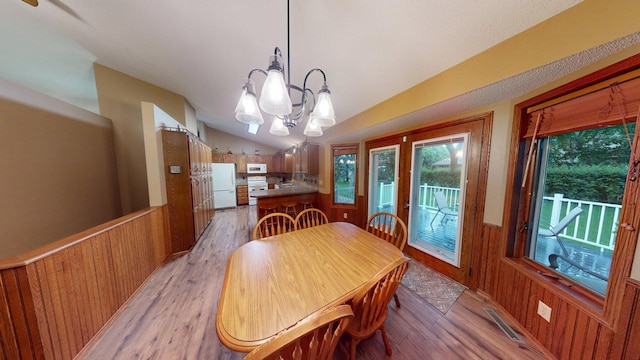 1715 Hansen Dr SW, Willmar, MN 56201 - dining room featuring light wood-type flooring, wainscoting, a chandelier, vaulted ceiling, and wooden walls