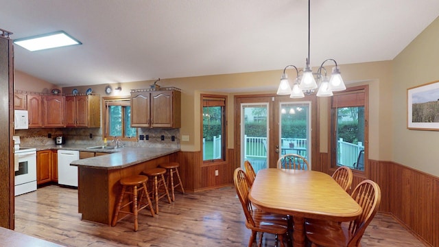 1715 Hansen Dr SW, Willmar, MN 56201 - kitchen featuring white appliances, wooden walls, a peninsula, a wainscoted wall, and light wood-style flooring
